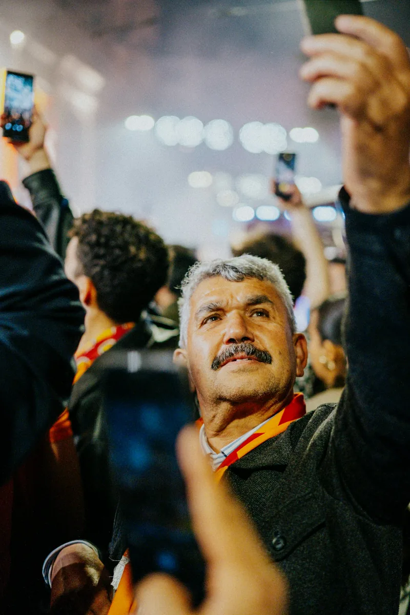 Sports fans holding smartphones in a crowded stadium